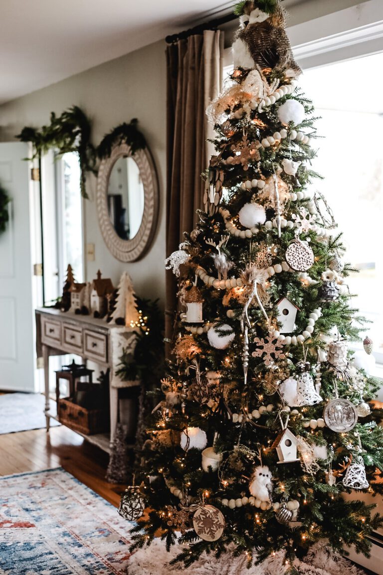 a decorated Christmas tree and a white entryway table and mirror