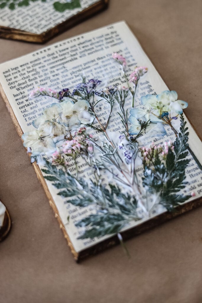 pressed flowers on a wood plaque that is wet with mod podge