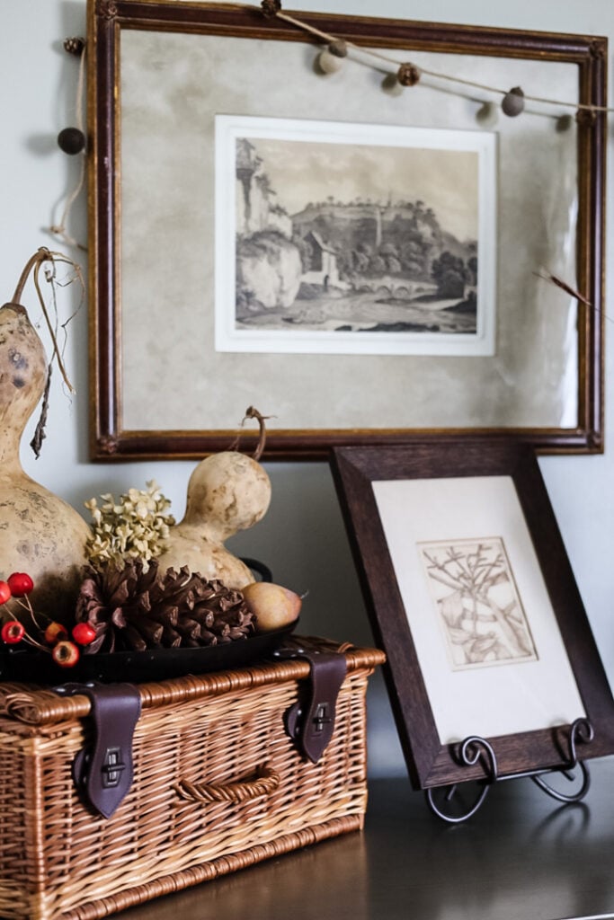 fall display with artwork, gourds, vintage basket