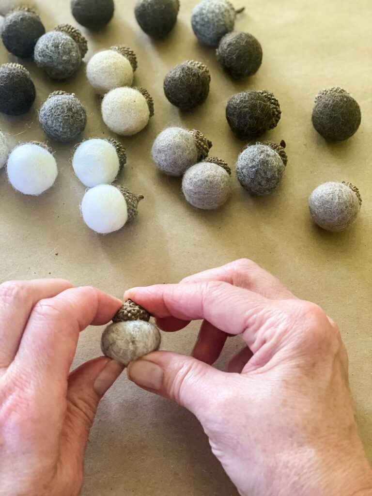 making diy felt acorns, hand holding acorn cap in place