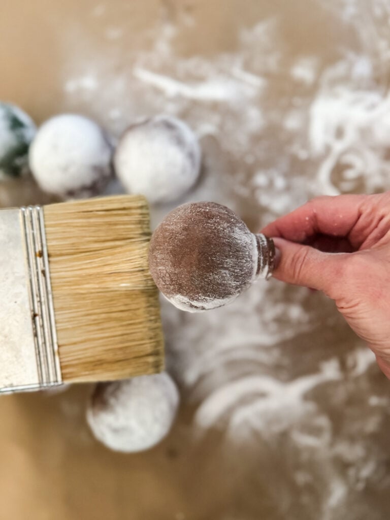 ornament makeover in progress, brushing baking soda off of an ornament
