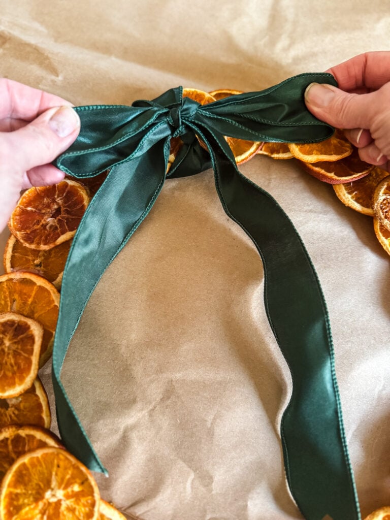 tying a dark green satin bow onto a wreath