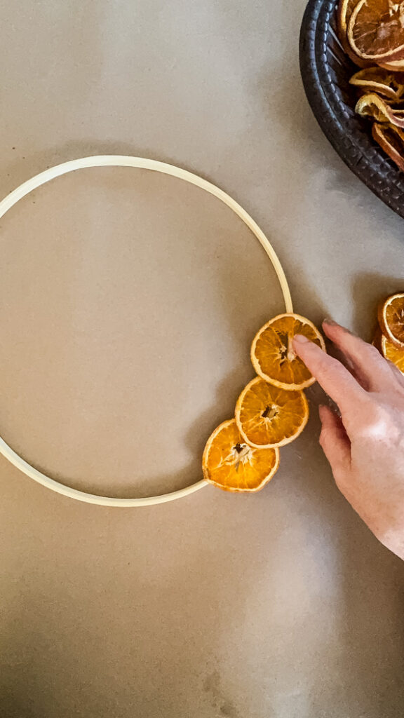 gluing dried orange slices onto a wreath