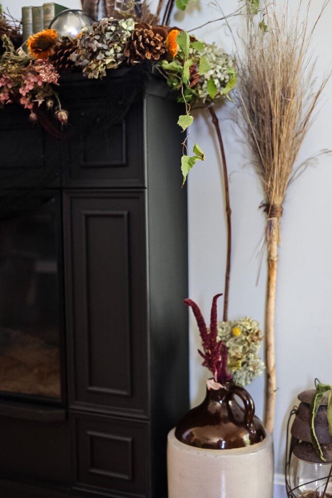 witch broom, jug, and old lantern next to black fireplace
