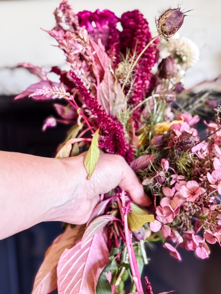 hand holding a variety of burgandy and pink flowers