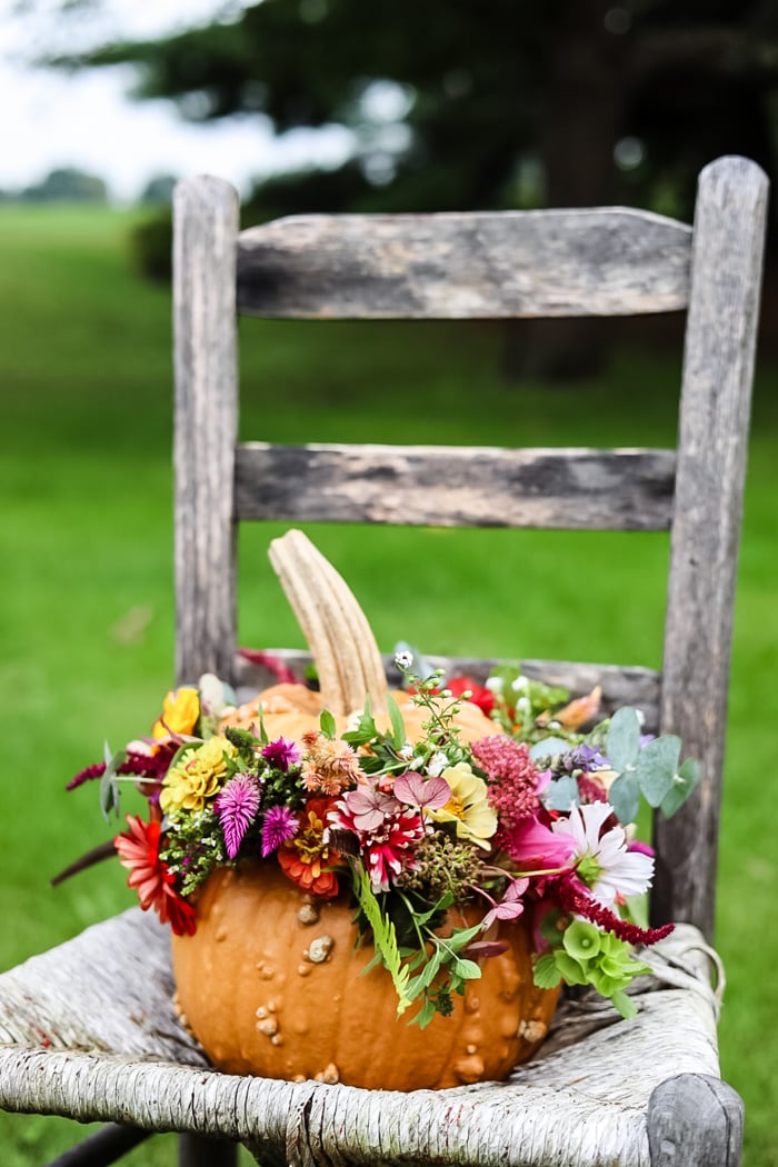 flower arrangement in a pumpkin on a chair