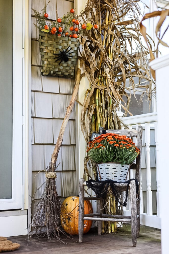 fall porch with witch broom and cornstalks.