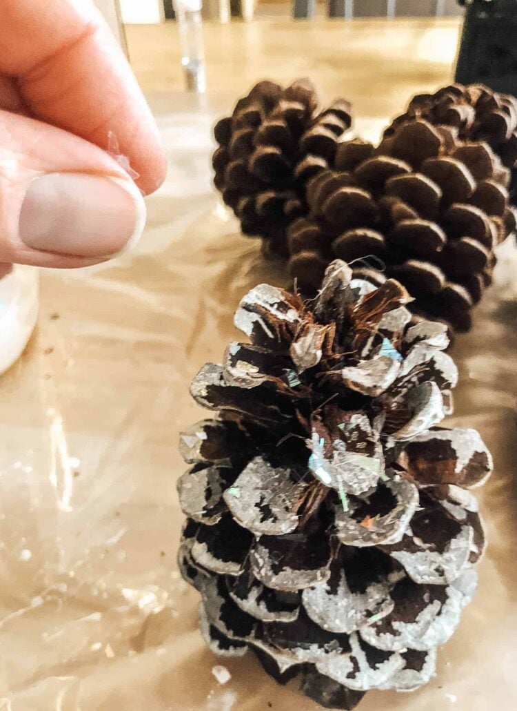 adding fake snow to a pine cone for a swag