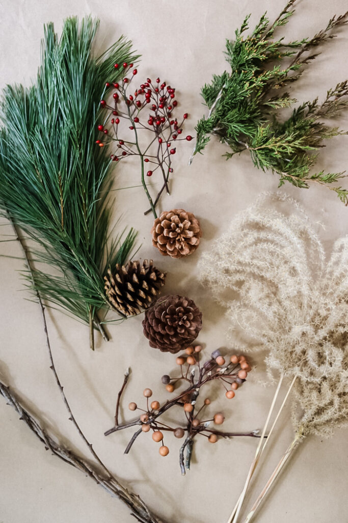 natural materials to make a wreath including greenry, pinecones, berries, and ornamental grass plumes